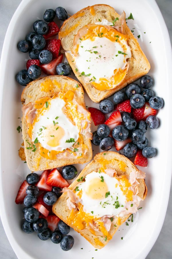 three pieces of toast with fried egg in the middle and surrounded by berries