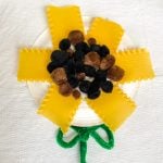 paper plate sunflower made from lasagna noodles and pompoms