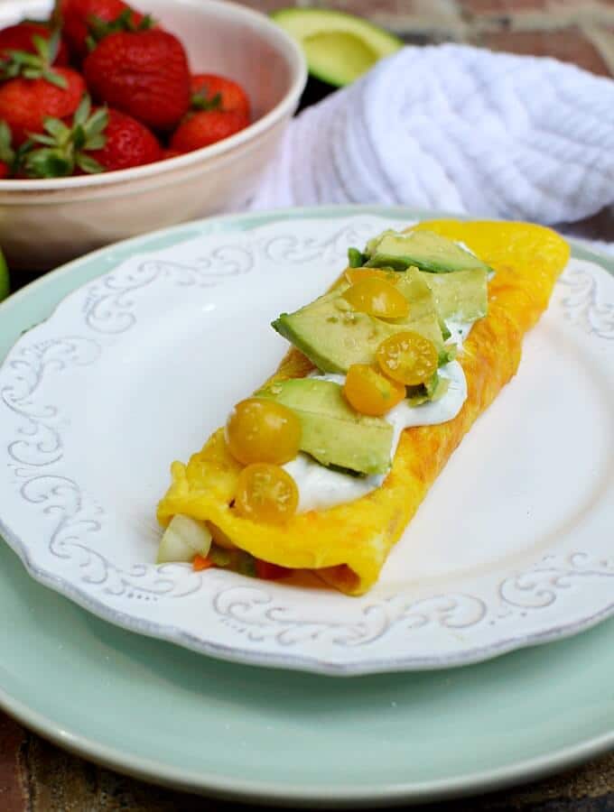 omelette with yellow tomatoes and avocado on a whit plate