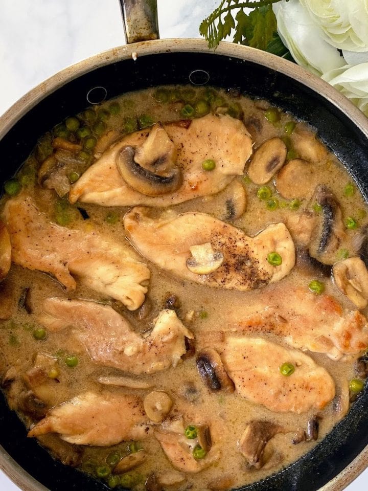 Marsala chicken with mushrooms and peas in pan