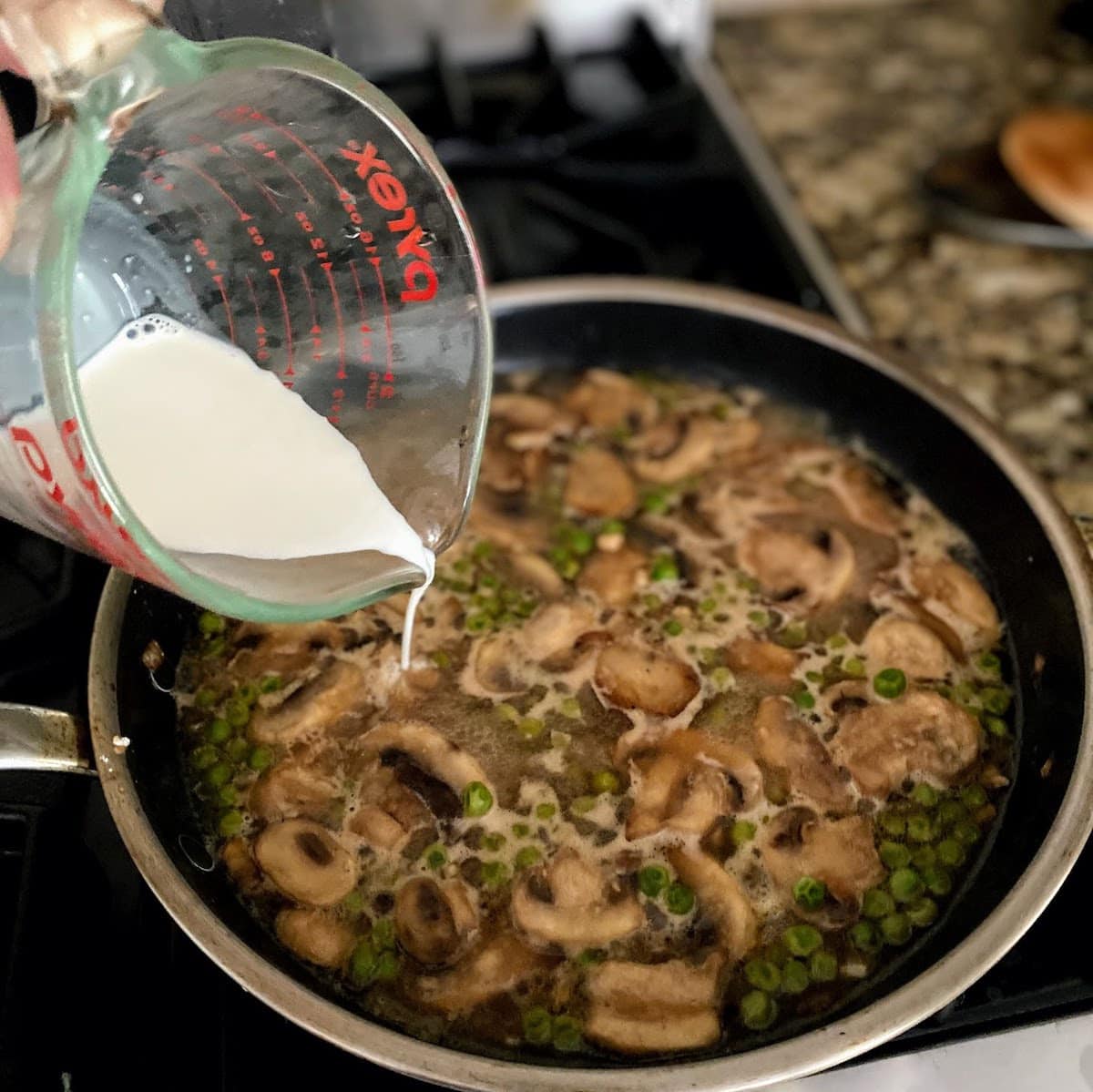 Pouring cream into pan of Marsala and mushroom sauce