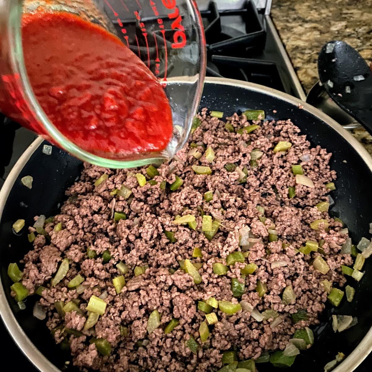 adding chili sauce to meat and veggie mixture for old fashioned sloppy joes recipe