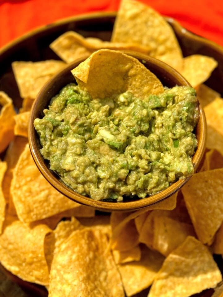 brown bowl filled with tortilla chips and guacamole dip