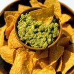 bowl of guacamole and tortilla chips on white table