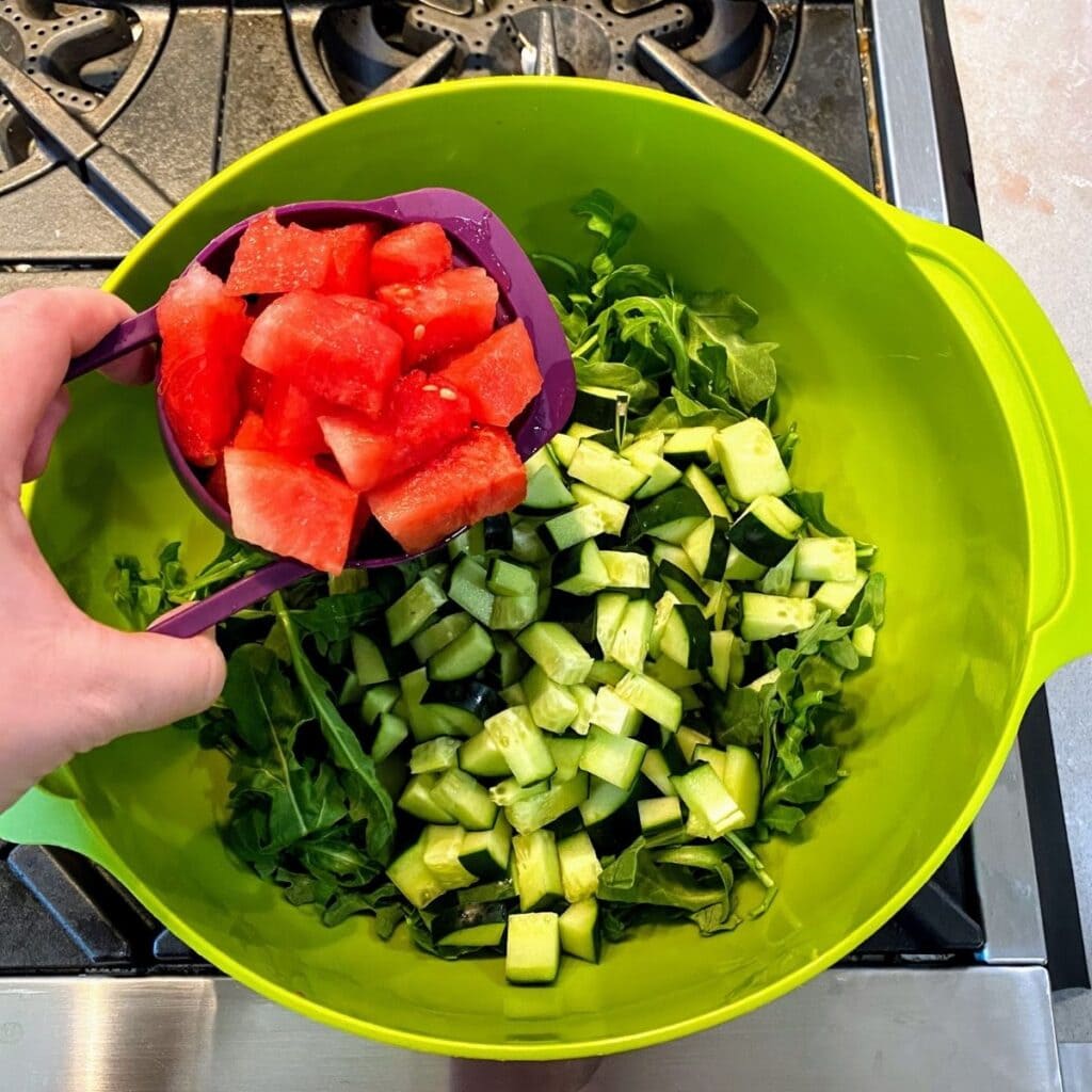 adding watermelon to salad