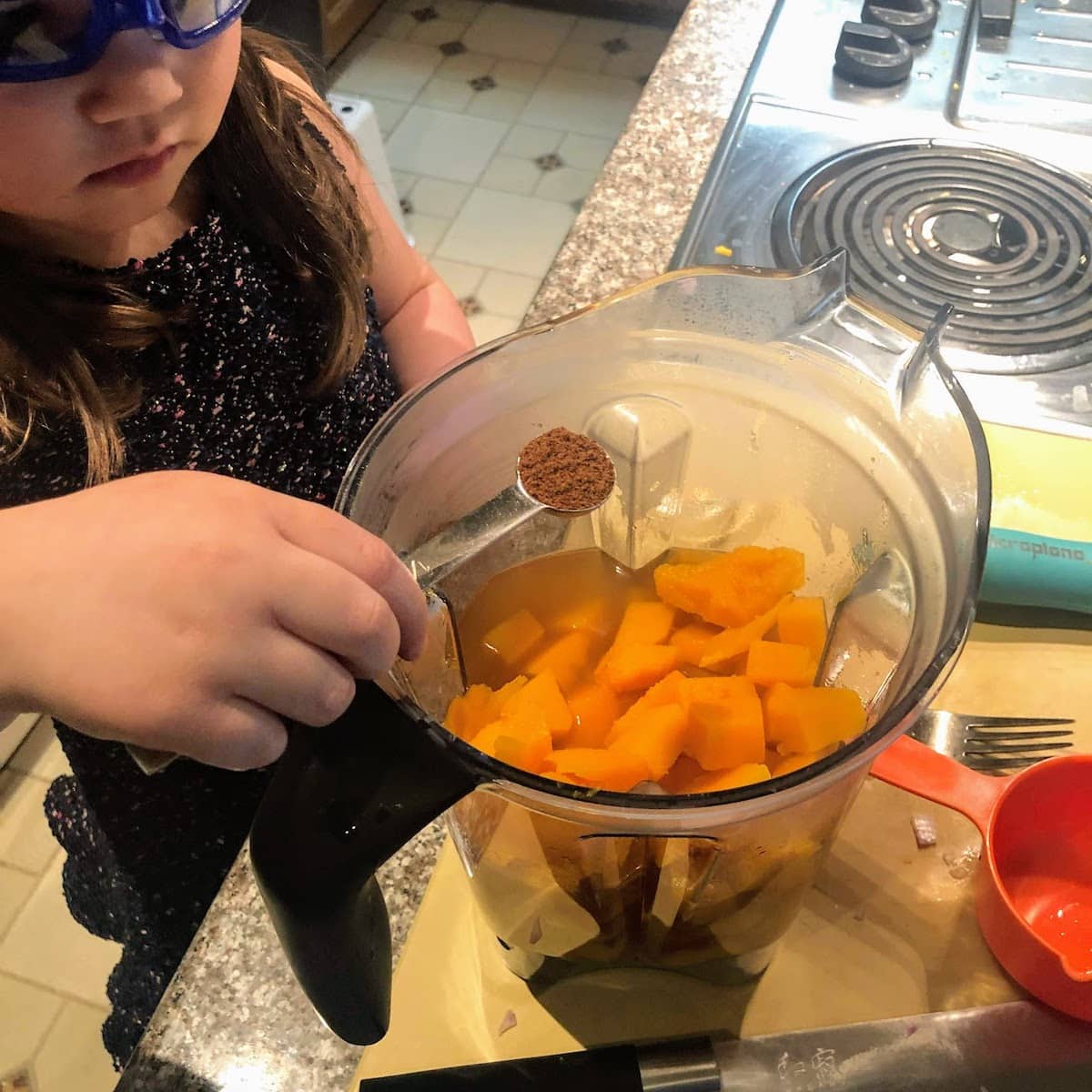 child adding seasoning to squash 