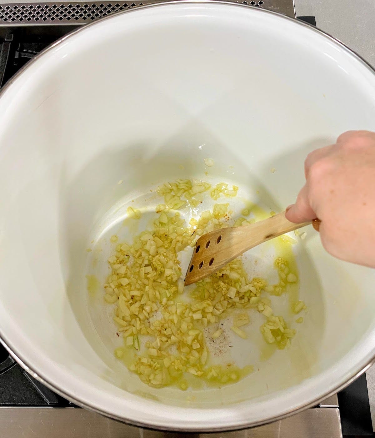 stirring onion and garlic in pot stovetop