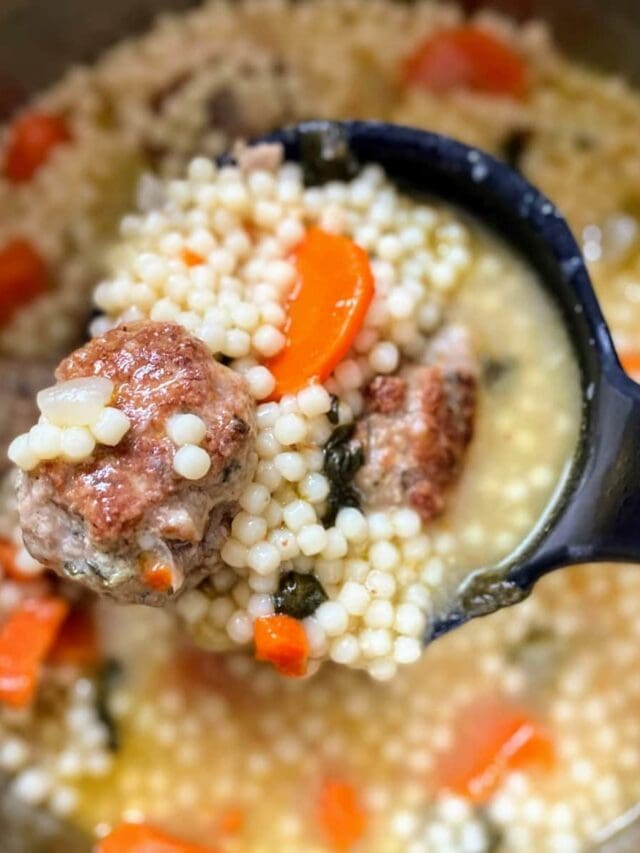 Ladle holding meatball and pasta in scoop of italian wedding soup.