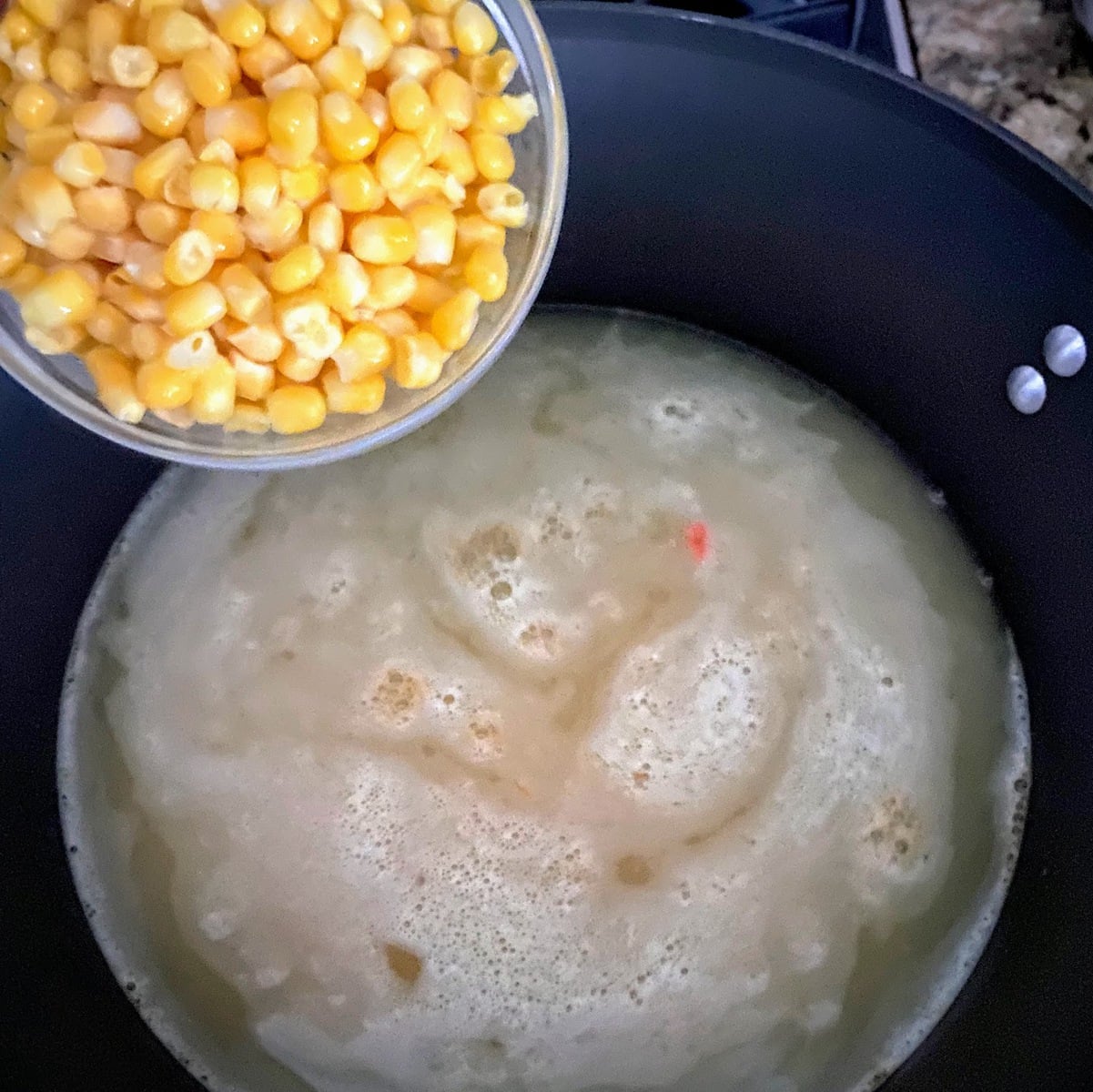 adding corn to broth in pot