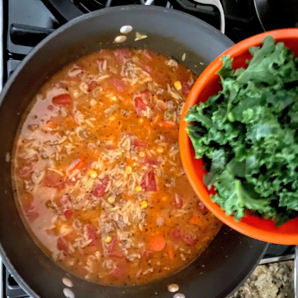 adding kale to pot of soup