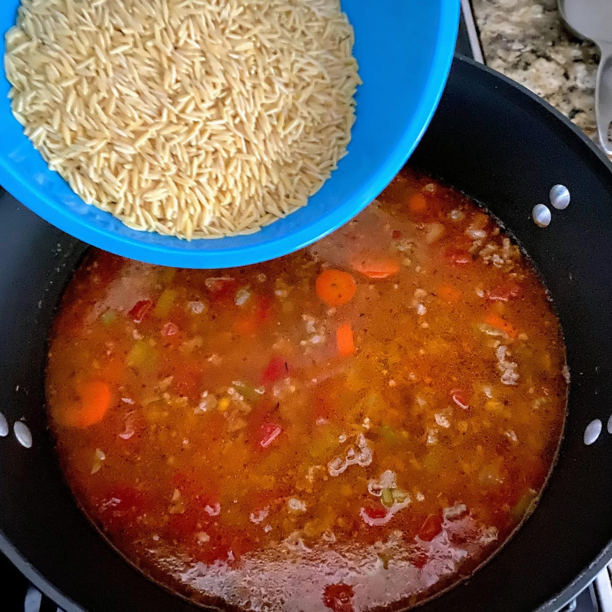 adding orzo to pot of broth and meat
