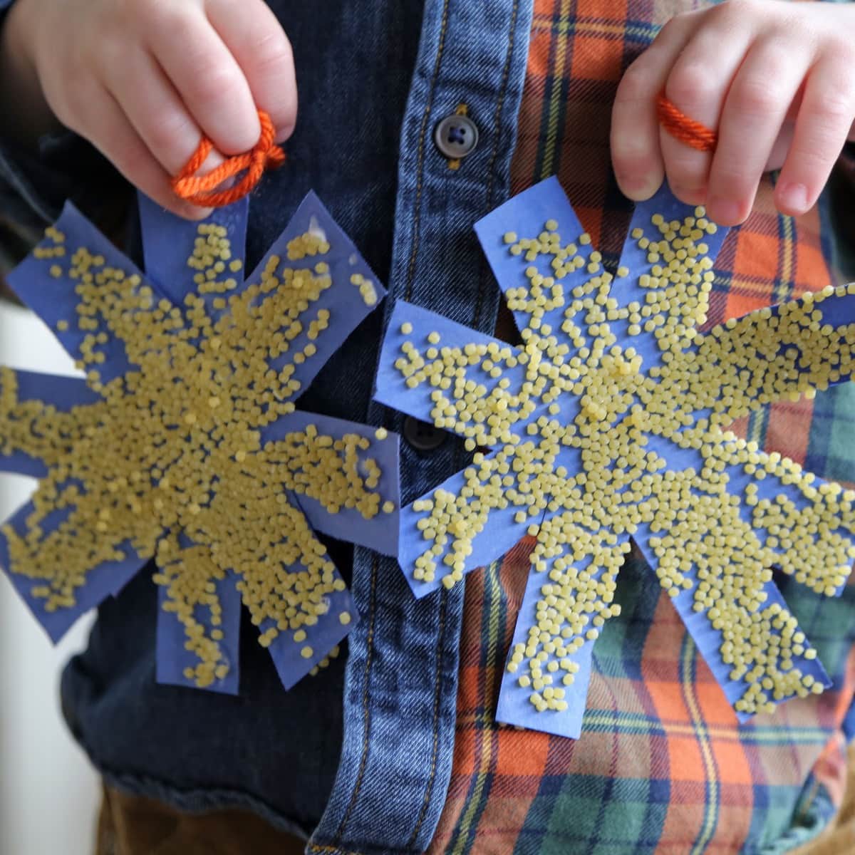 two paper snowflakes with pasta