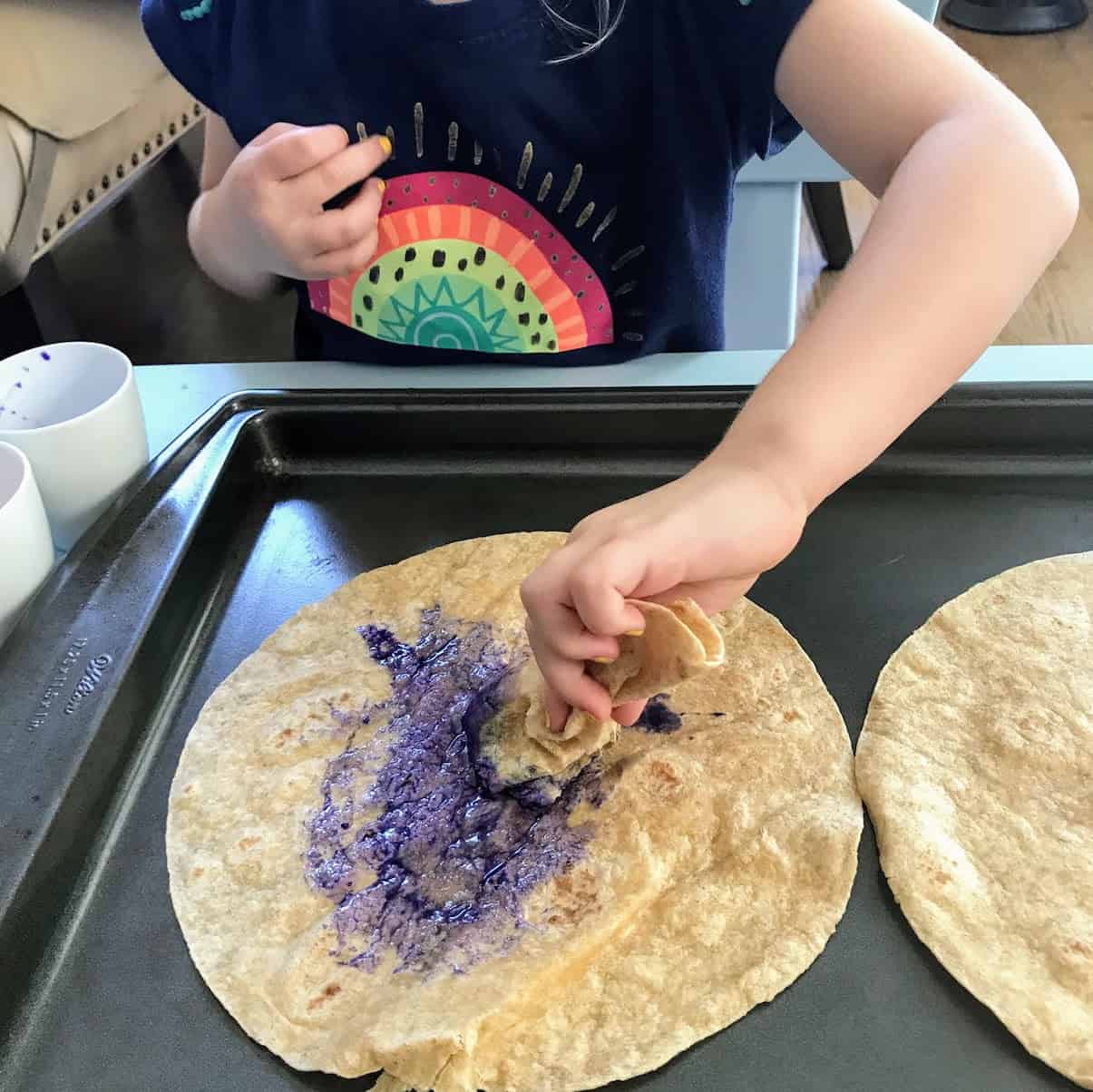 child mixing water and food coloring in small dish