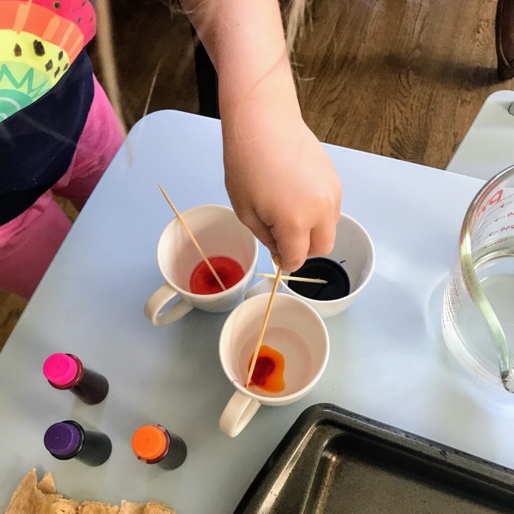 child mixing water and food coloring