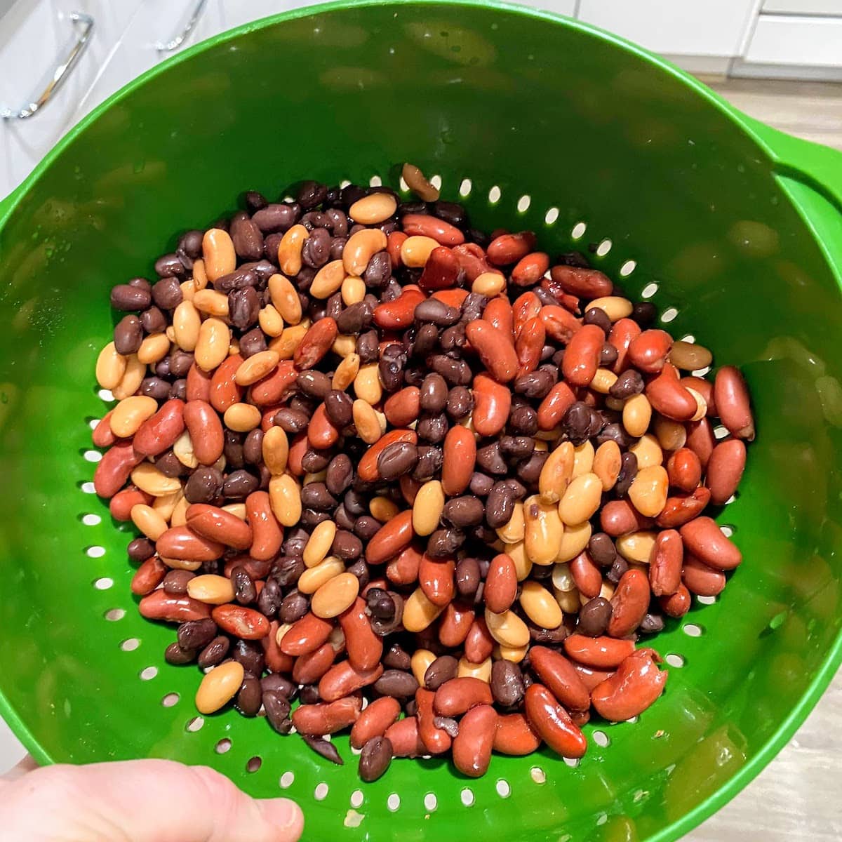 three kinds of beans in a bright green colander