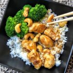 chicken and cashews with chopsticks atop white rice