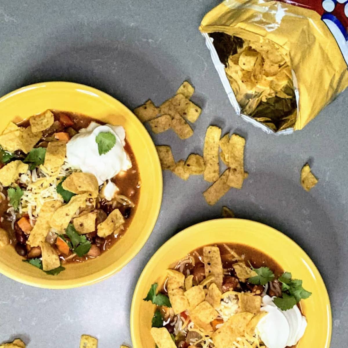 two chili bowls with corn chips sprinkled around
