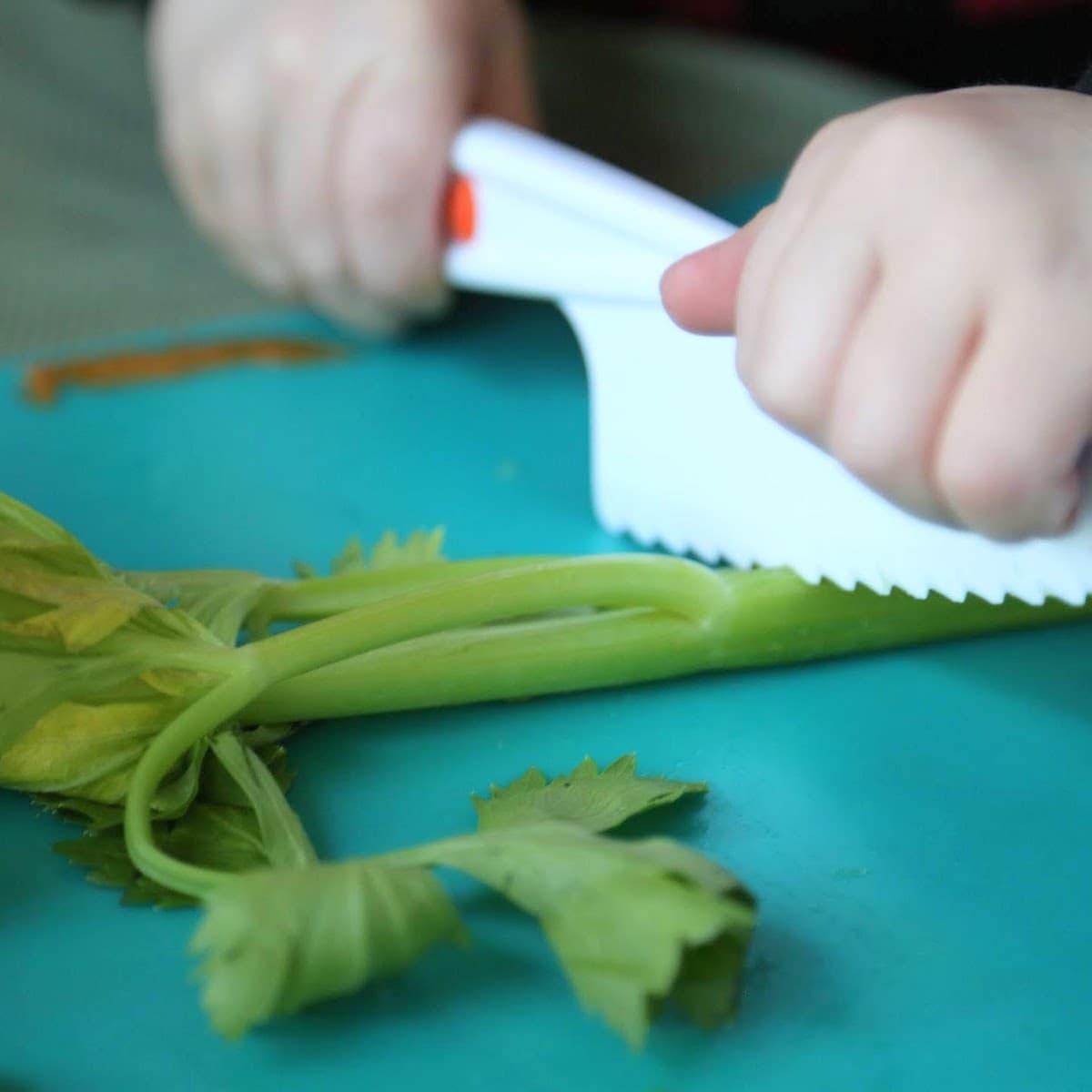 child cutting celery on a teal cutting board