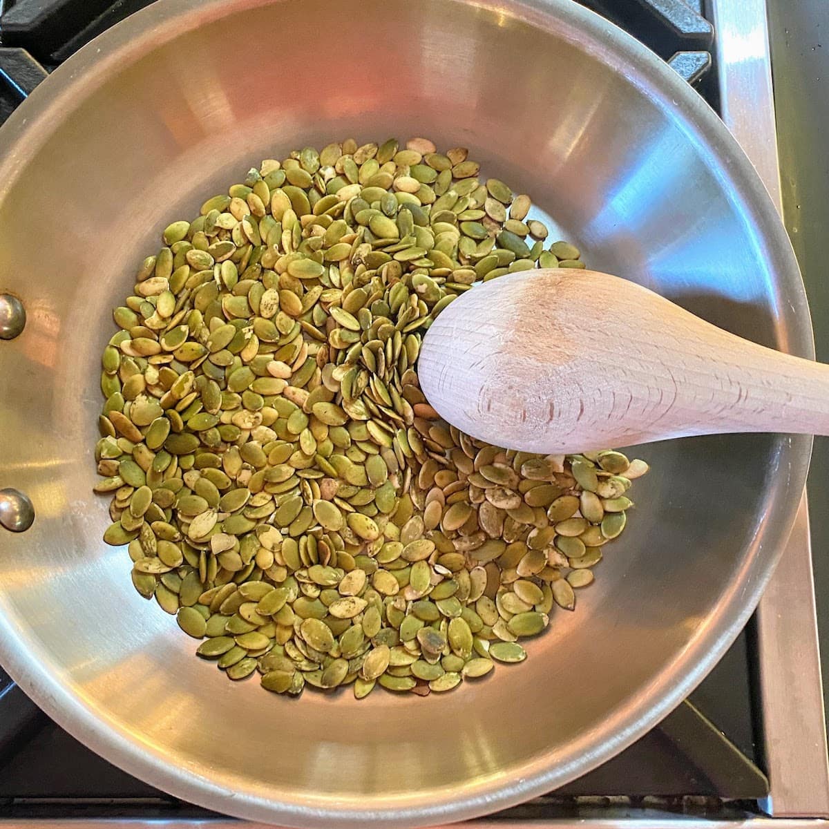 pumpkin seeds in pan being stirred