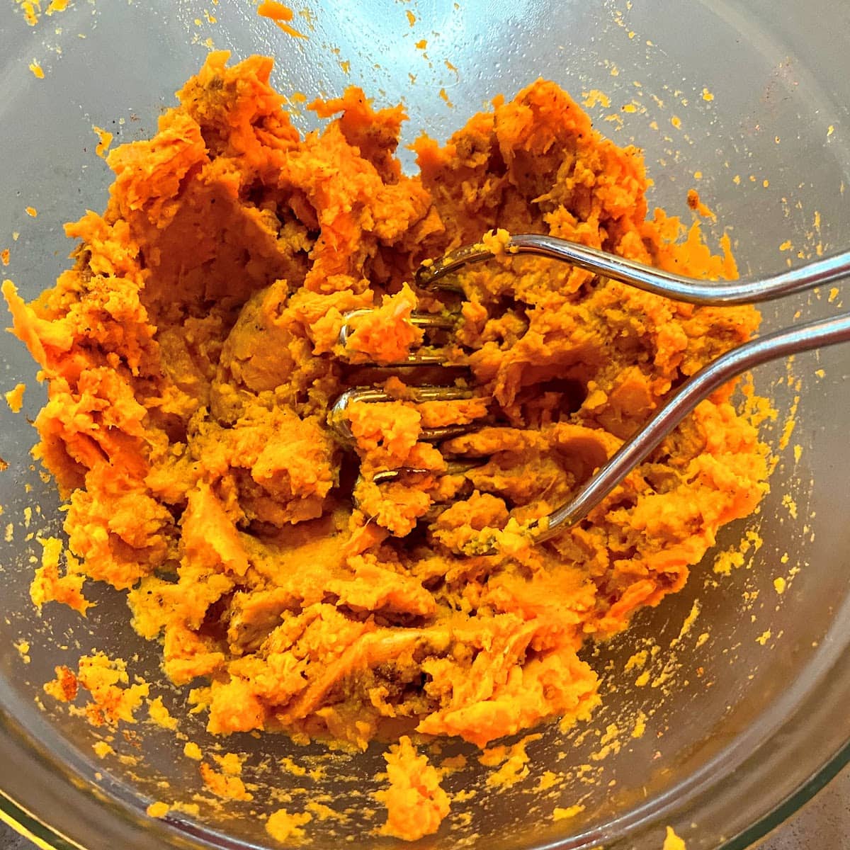 mashing cooked sweet potatoes in a bowl
