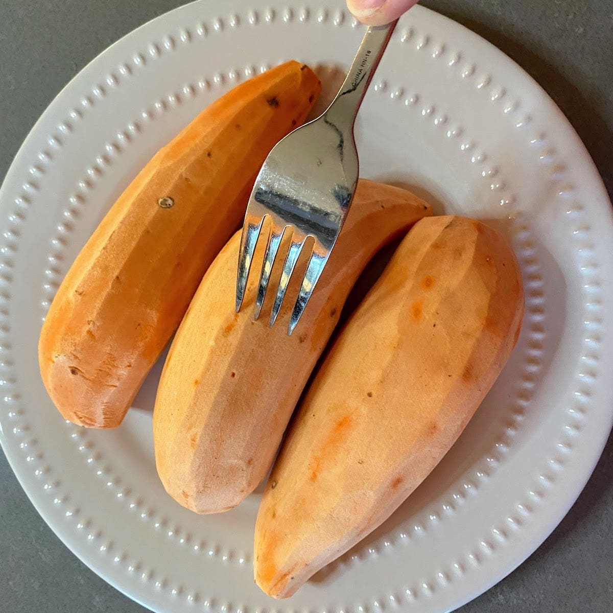 stabbing peeled sweet potatoes with a fork