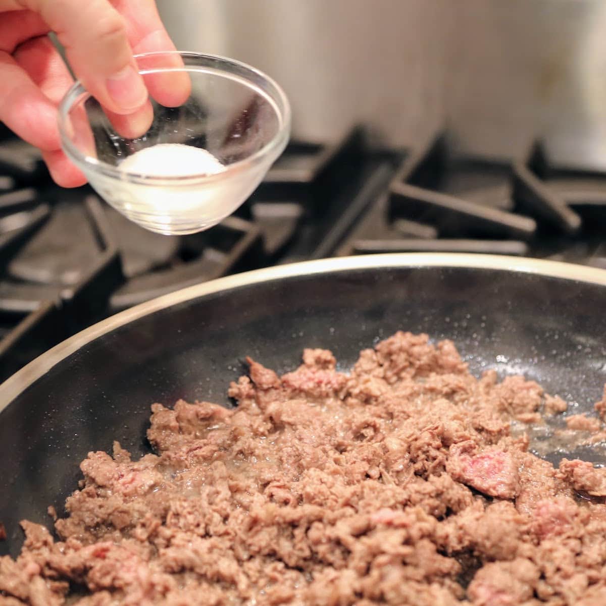 adding salt to pan of shaved beef