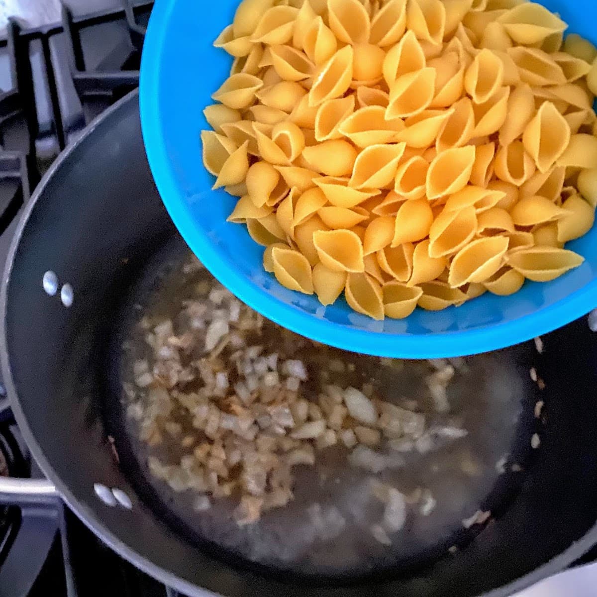 adding pasta to onion and garlic and broth