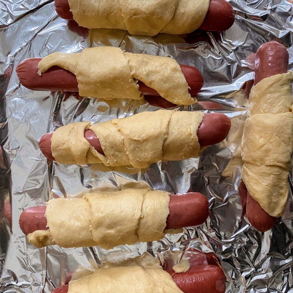 crescent hot dogs raw on baking sheet
