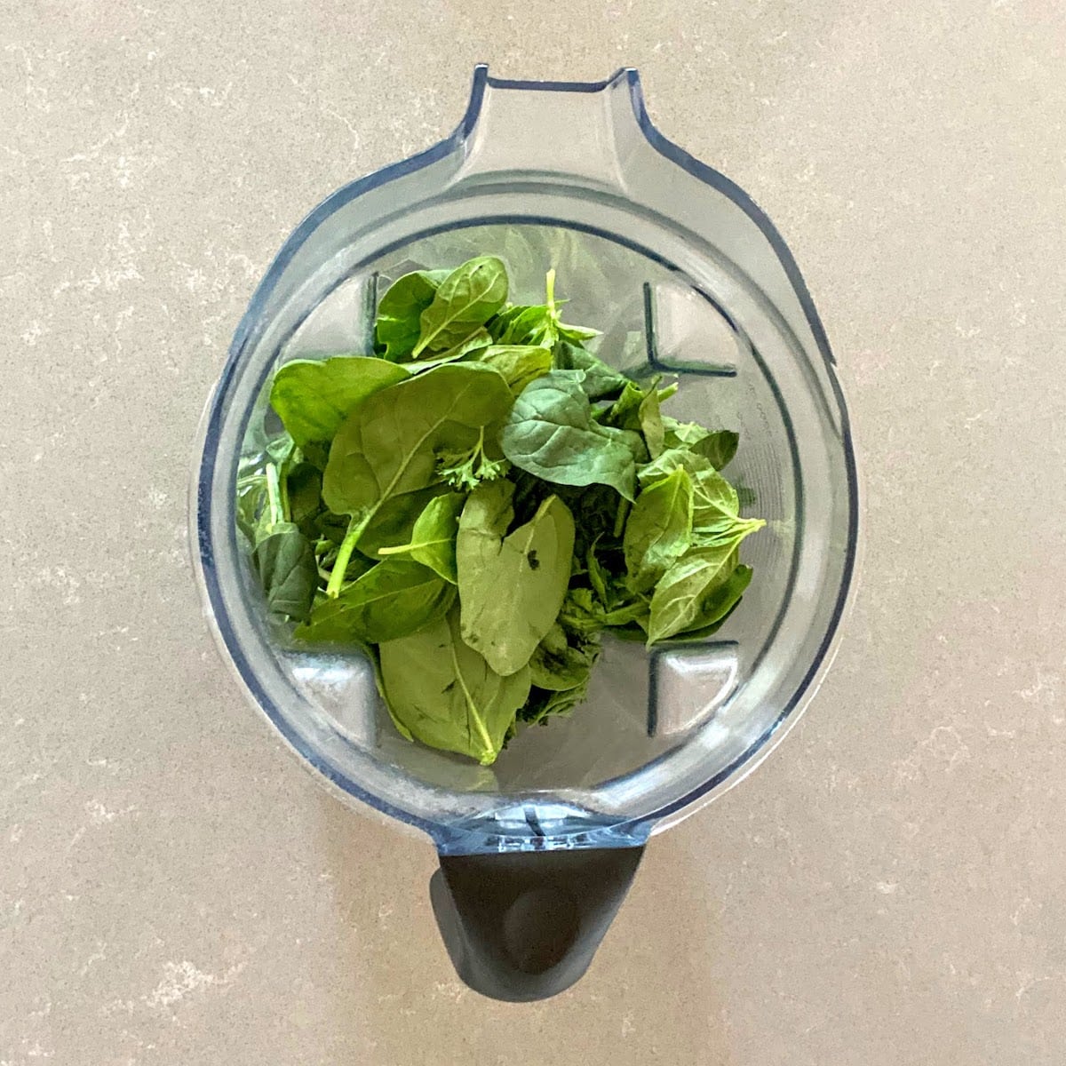 spinach, basil and parsley in vitamix container