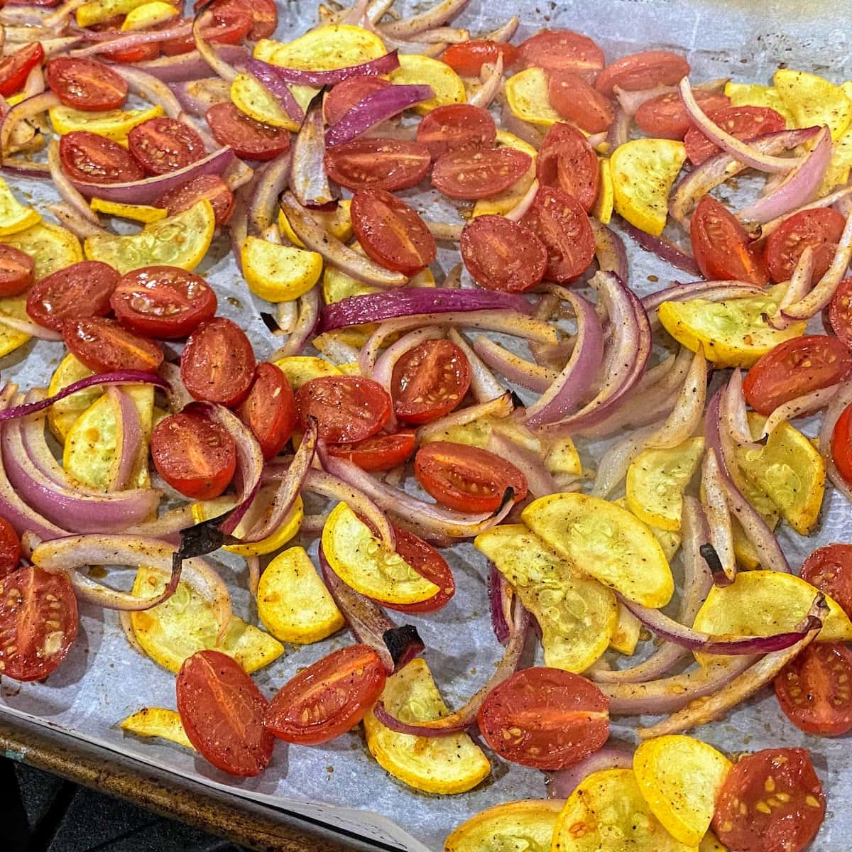 sheet pan full of roasted tomatoes, summer squash and red onion