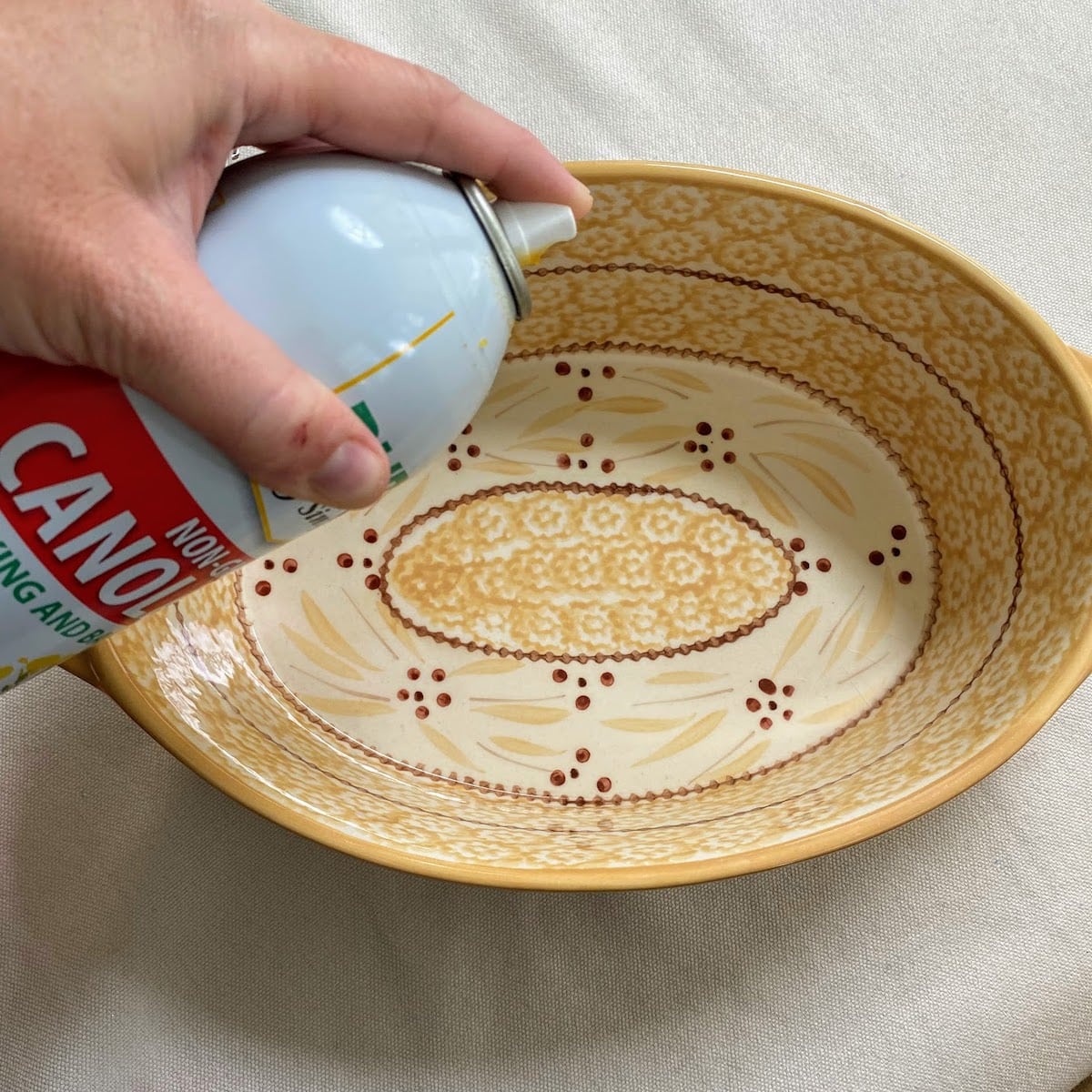 spraying casserole dish with oil 