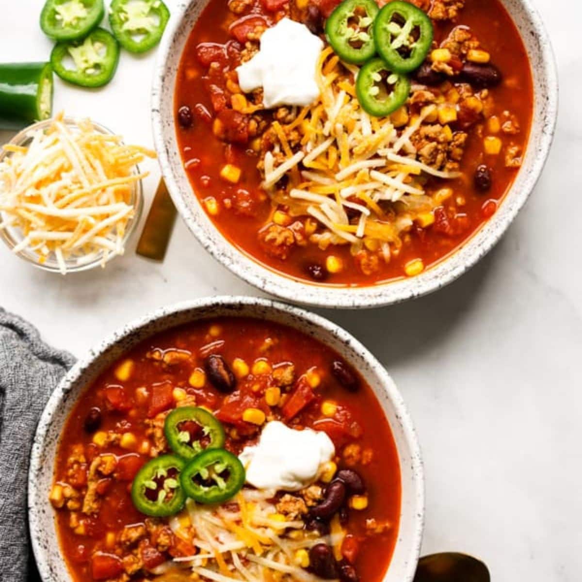 two bowls of turkey chili topped with sour cream and cheese
