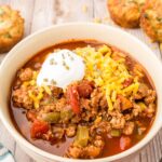 A bowl of ground turkey chili with cheese and sour cream