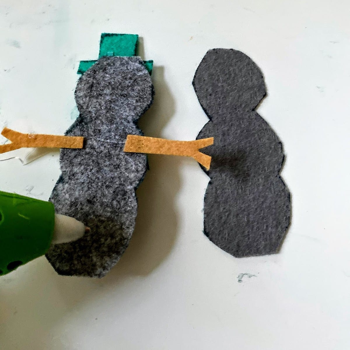 Gluing two pieces of felt snowman together with hot glue gun