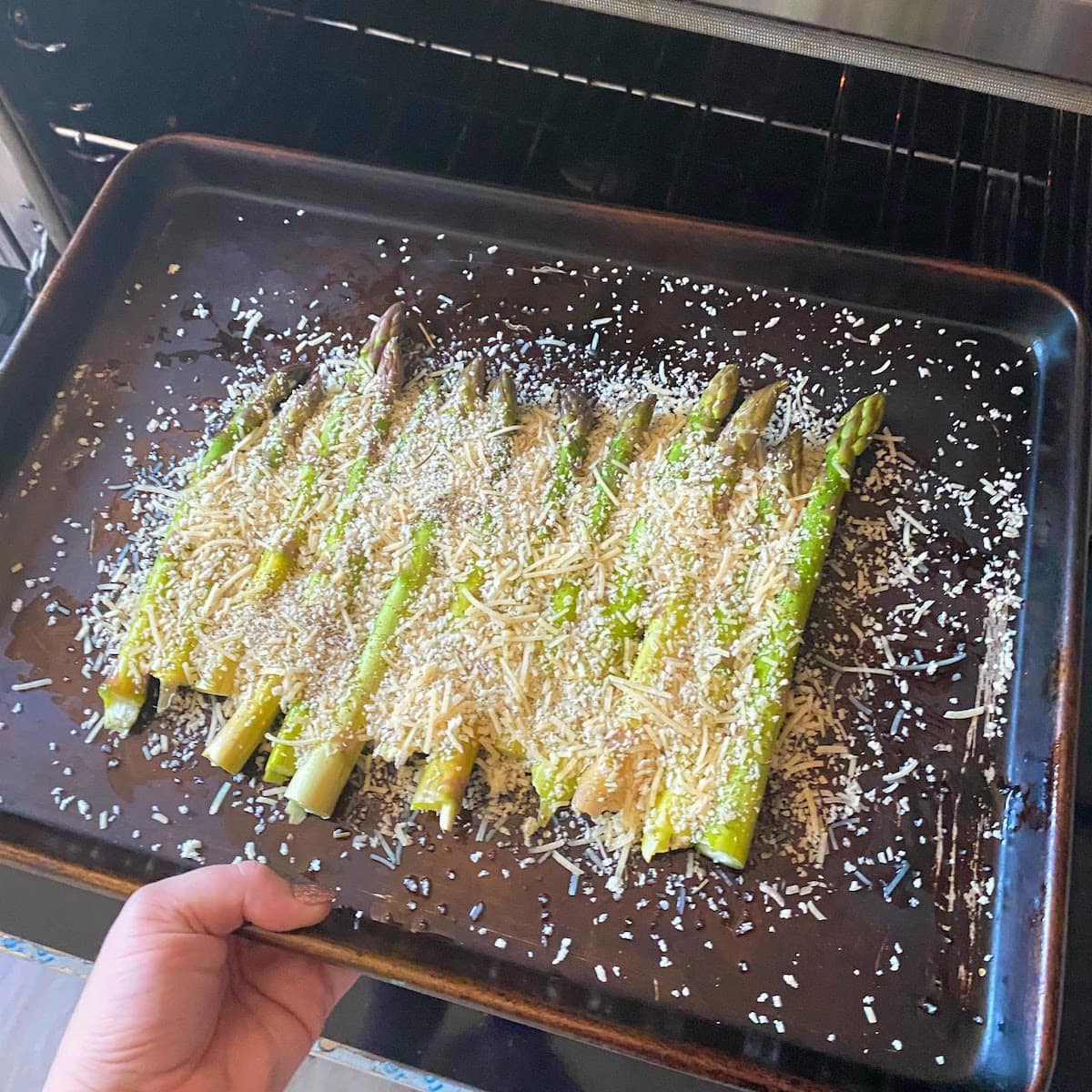 putting pan of parmesan crusted asparagus into oven