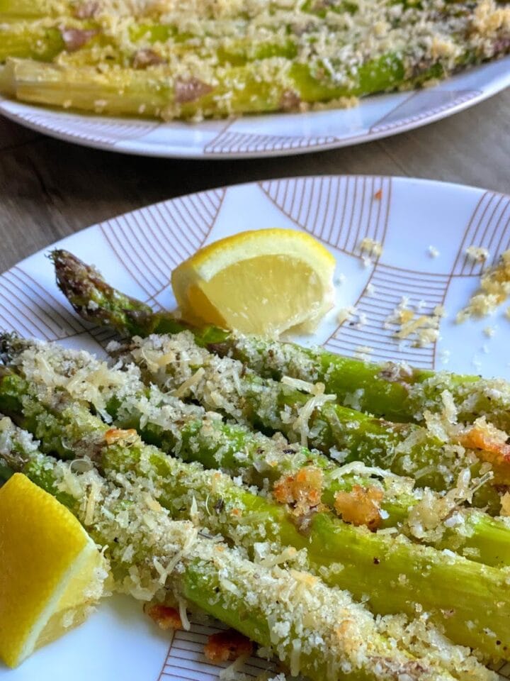 plates of breaded asparagus with lemon wedges