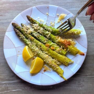 plate with roasted asparagus, lemon and fork