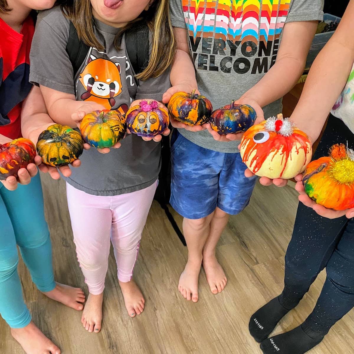 four kids holding the colorful mini pumpkins they made