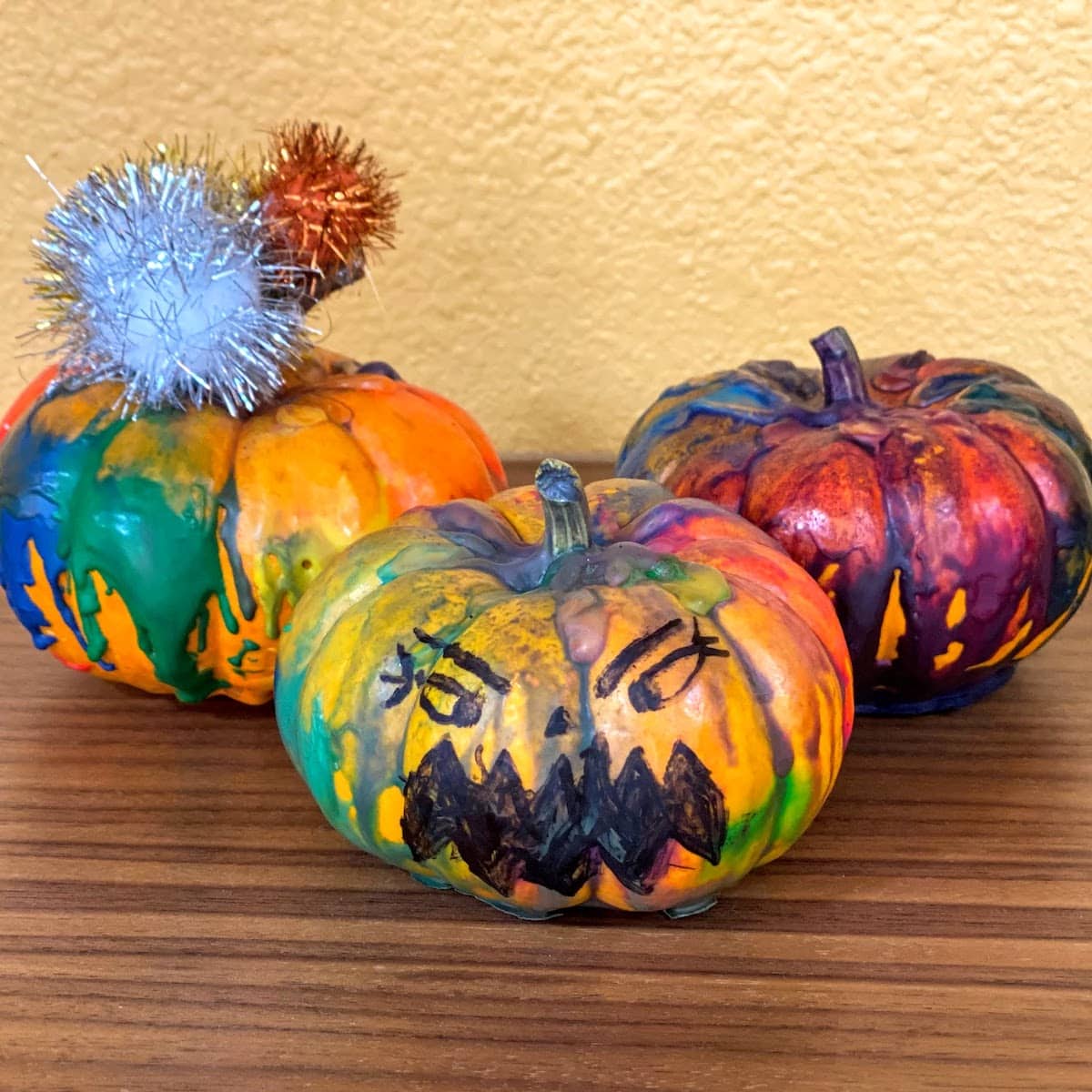 three mini pumpkins with colors and faces