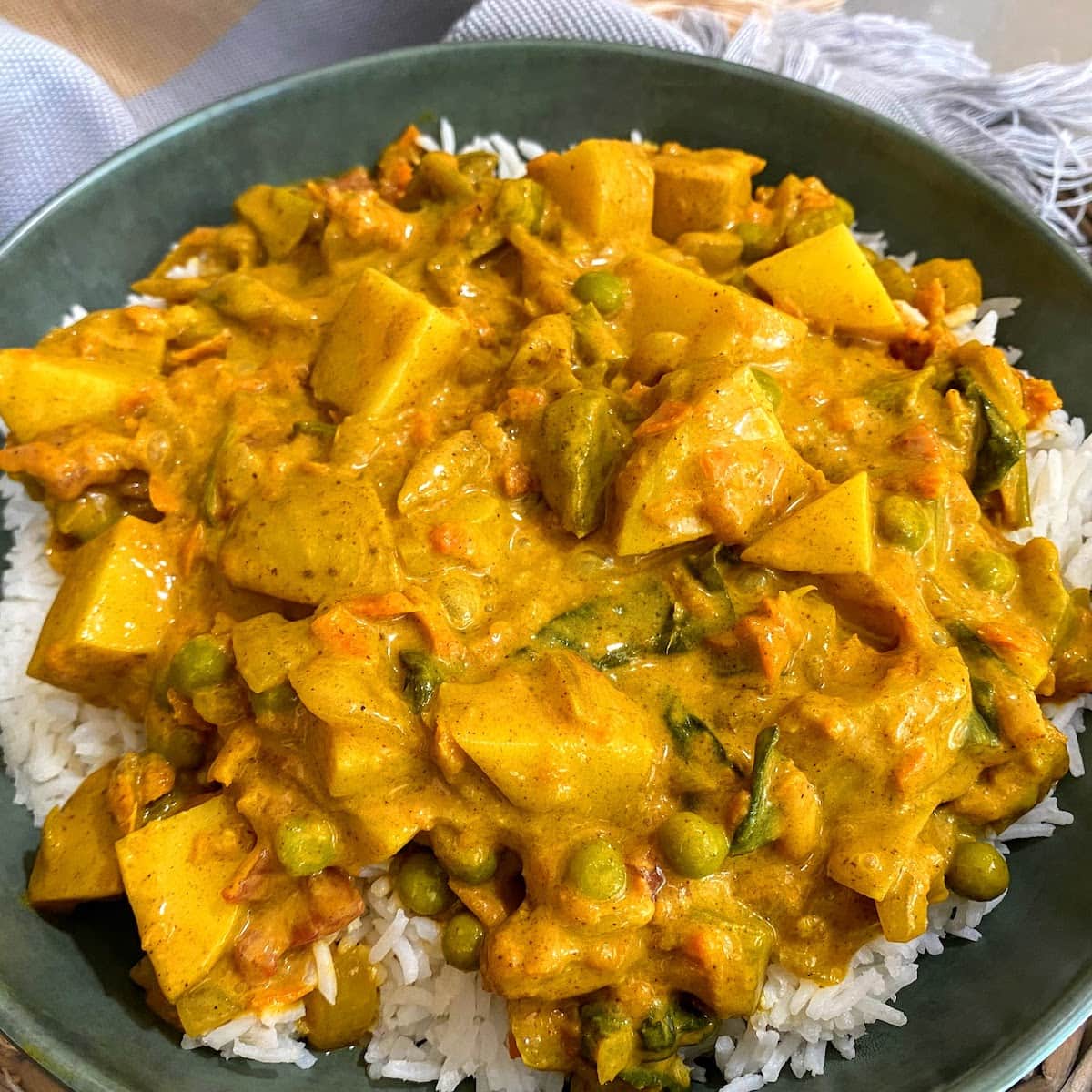 closeup view of creamy coconut curry over rice in green bowl
