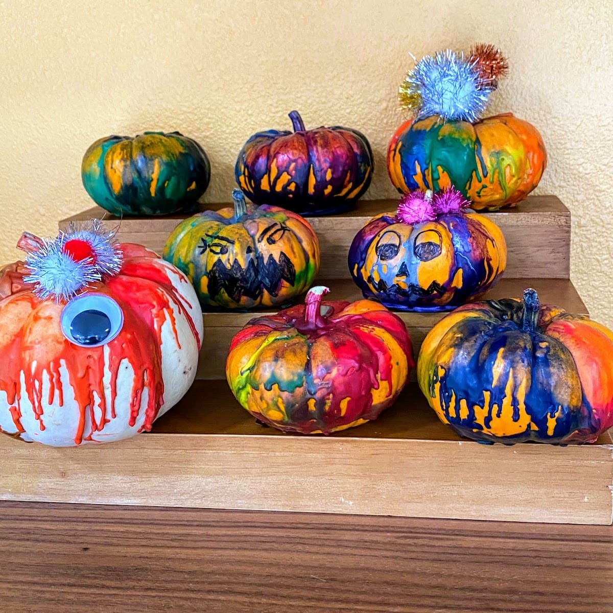 eight colorful pumpkins sitting on staggered shelf