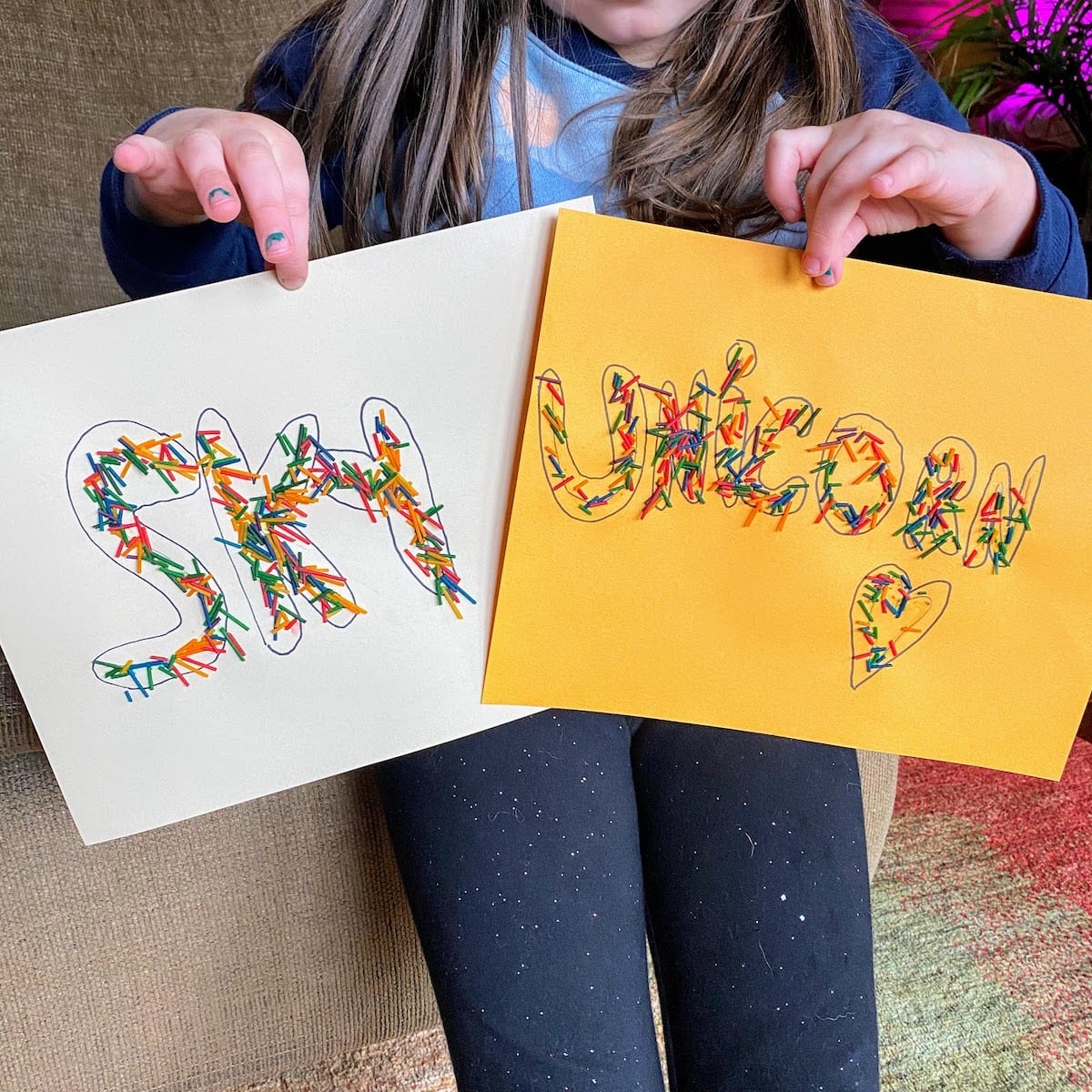 child holding sings with rainbow letters for unicorn and sky 