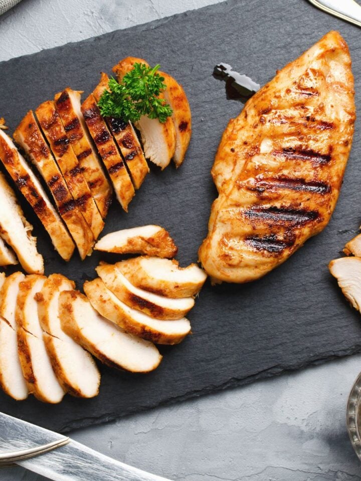 sliced chicken on slate serving platter with mustard and utensils