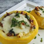 squash stuffed with sausage, cheese and veggies on white tray