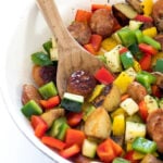 sausage and veggies in bowl with wooden spoon