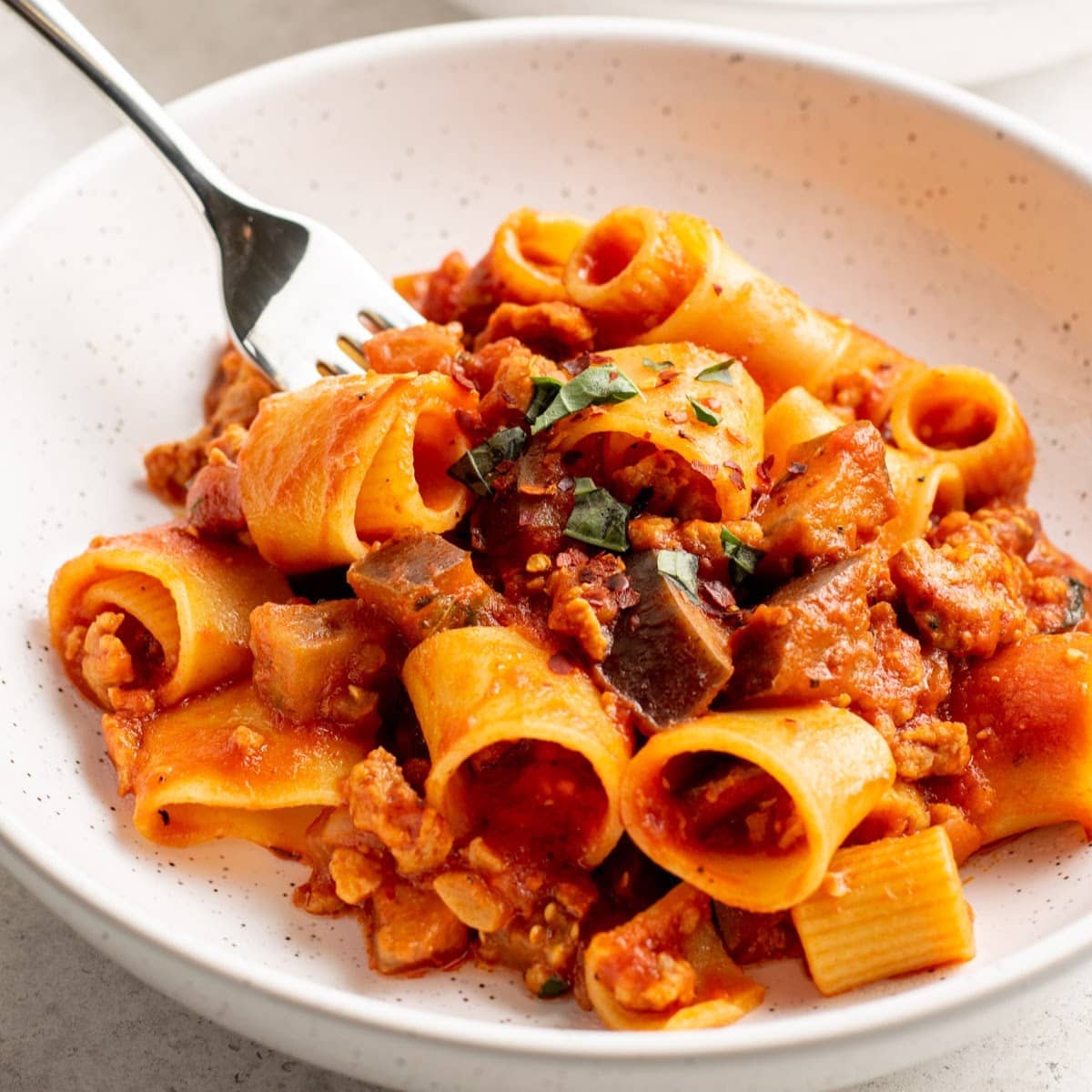 sausage and pasta in white bowl with red sauce