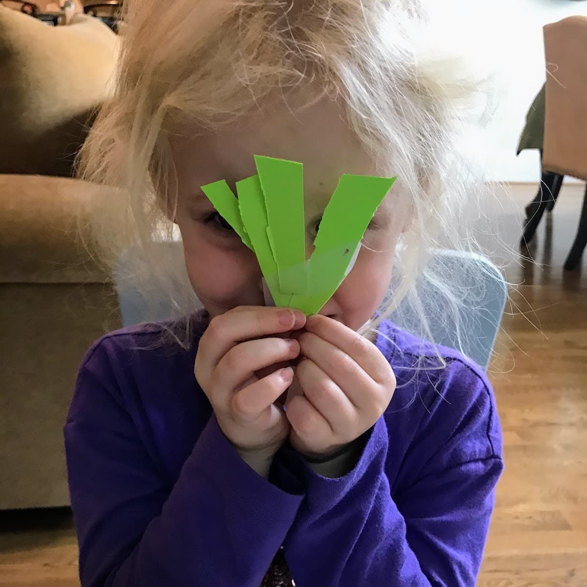 child holding green strips of paper