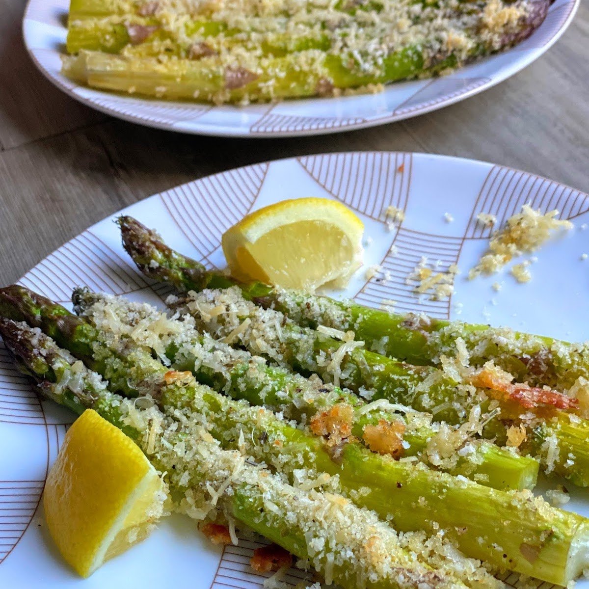plates of breaded asparagus with lemon wedges
