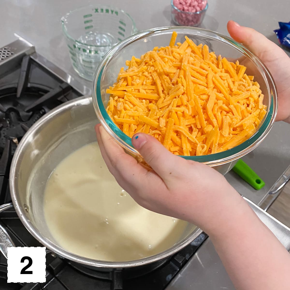 adding shredded cheese to creamy sauce