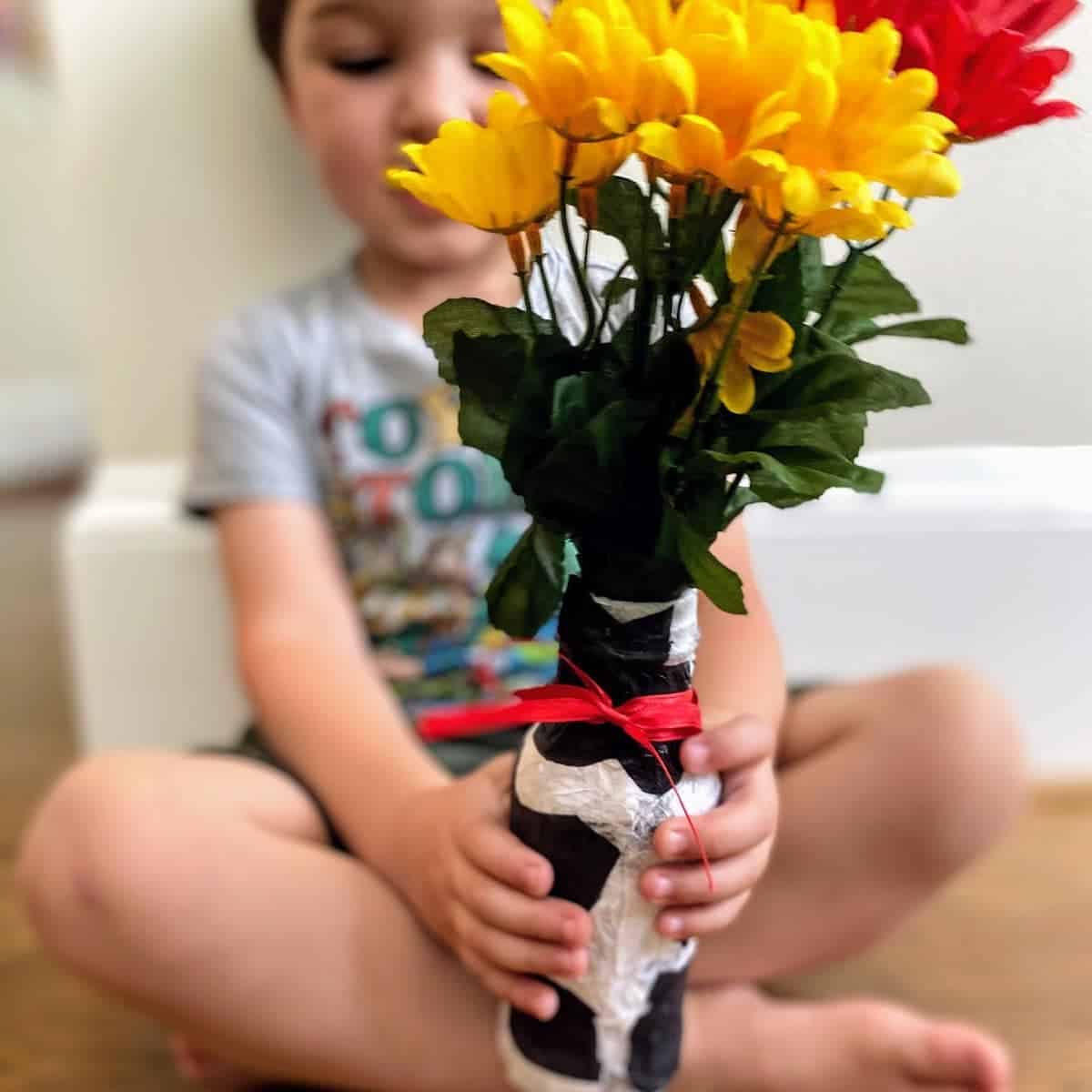 child holding tissue paper vase with flowers